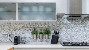 A modern kitchen with a tiled backsplash, stainless steel appliances, and minimalist cabinetry.