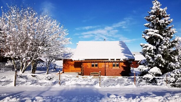 A wooden cabin with a snow-covered roof, surrounded by snow-laden trees and a clear blue sky. - Les 7 Coeurs, cosy chalet in Val Foncine (Foncine-le-Haut)