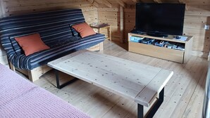 A cozy cabin interior with a striped sofa, a television, and a wooden table. - Les 7 Coeurs, cosy chalet in Val Foncine (Foncine-le-Haut)