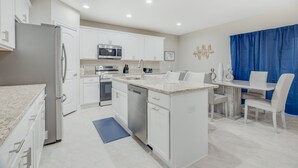 A modern kitchen with white cabinetry, a stainless steel refrigerator, a microwave, and a dishwasher.