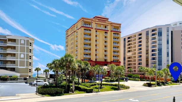 A multi-story hotel with balconies, a parking area, and well-maintained landscaping.