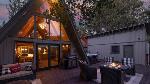 A modern house with a large glass window, a deck with outdoor furniture, and a barbecue grill. - Amazing A Frame w/ Gorgeous Views of Bear Mountain + Spa (Big Bear Lake)