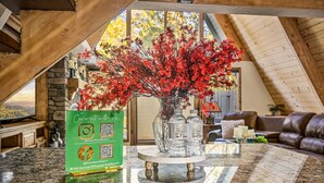 A wooden interior with a stone fireplace, a vase with red flowers, and a QR code sign. - Amazing A Frame w/ Gorgeous Views of Bear Mountain + Spa (Big Bear Lake)