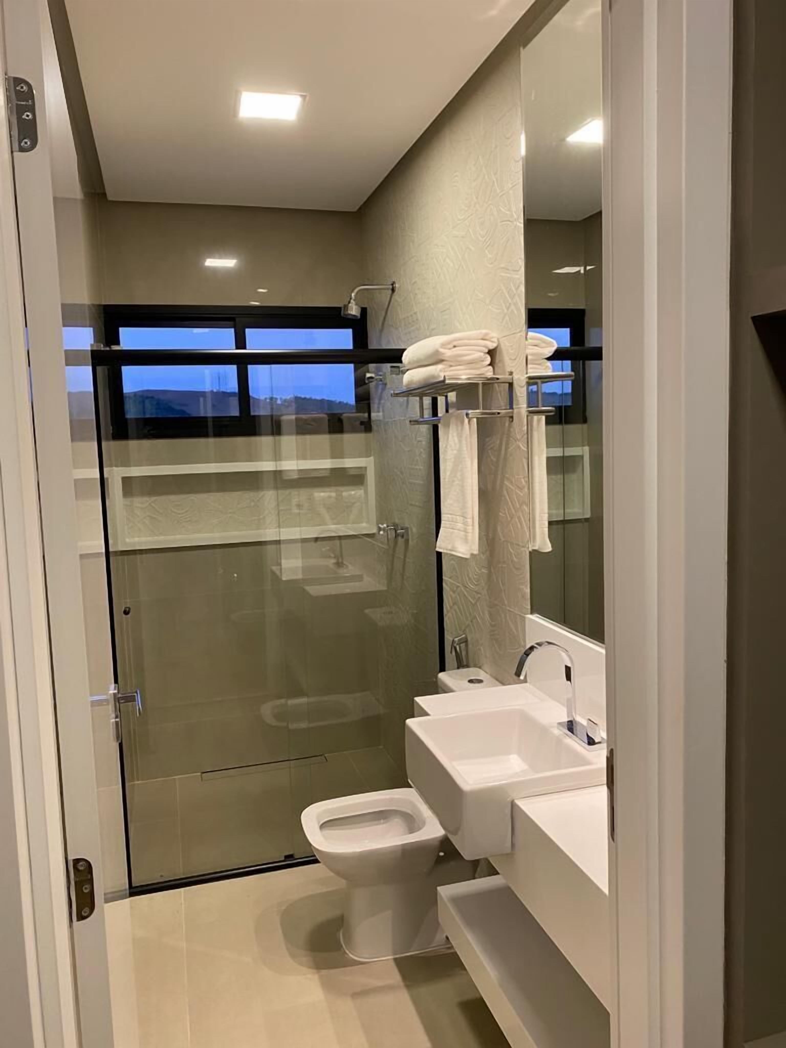 Een moderne badkamer met een douchecabine van glas, een toilet en een wastafel met spiegel.