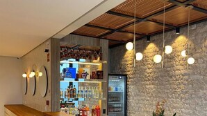 A modern bar area with a wooden ceiling, a blue counter, and bar stools. - Vista do Lago Hotel (Capitólio)