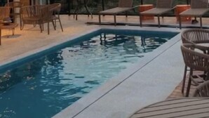 A modern outdoor pool area with lounge chairs and a view of mountains. - Vista do Lago Hotel (Capitólio)