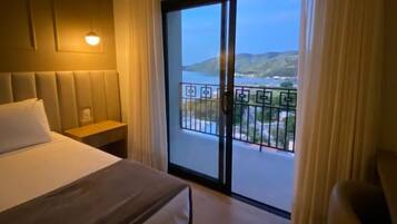 A hotel room with a bed, bedside table, and a view of a balcony with a railing.