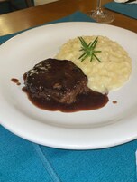 A plate with a steak and mashed potatoes, garnished with a sprig of rosemary.
