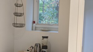 A kitchen with a wooden cart, a blender, a kettle, and a window with a view of trees. - Private two story guesthouse in Takoma Park (Takoma Park)