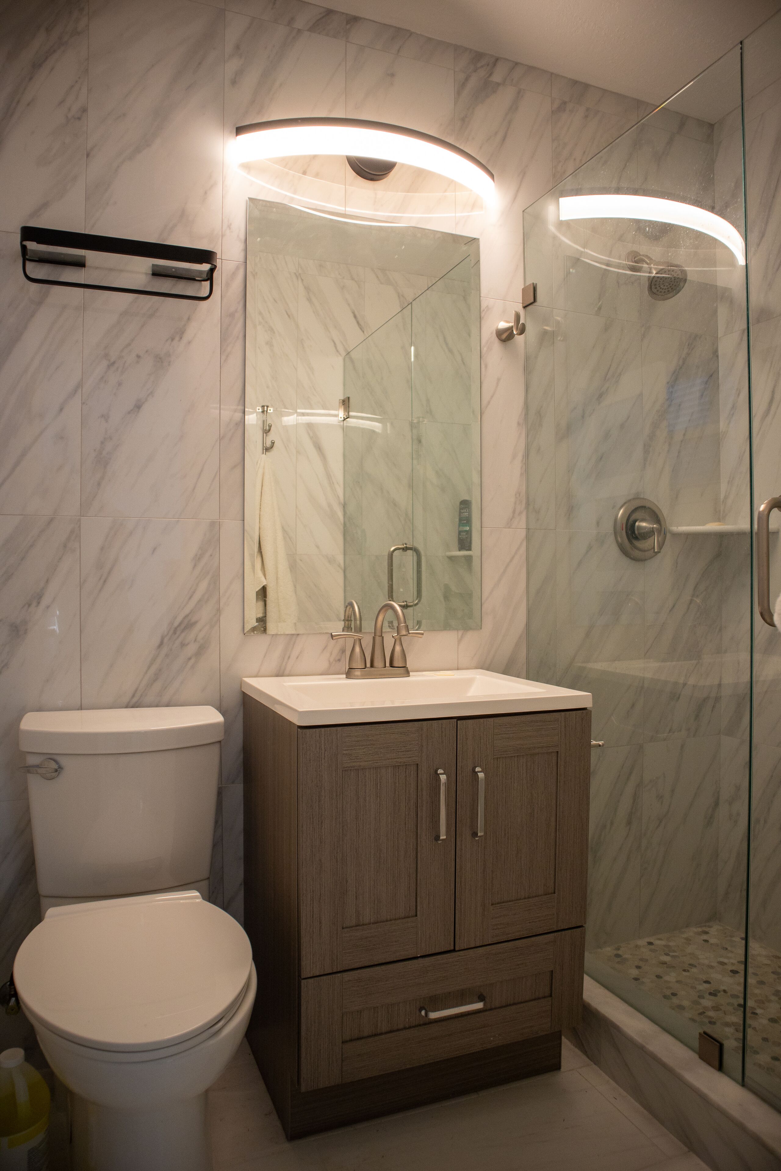 A modern bathroom with a toilet, sink, and glass shower enclosure.
