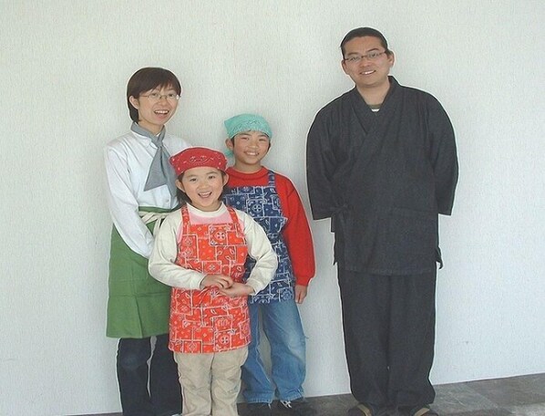 A group of people standing against a plain wall.