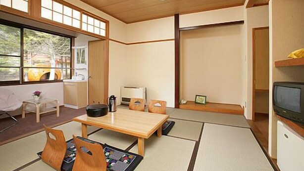 Una habitación tradicional japonesa con suelo de tatami, una mesita baja y puertas correderas.