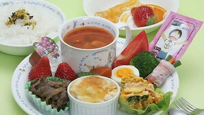 Un plato con diferentes alimentos, como arroz, sopa, fresas y verduras.