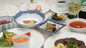 Una mesa dispuesta con diferentes platos, incluyendo un tazón de sopa, un plato con verduras y una taza de café.