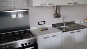 A kitchen with a stove, sink, and cabinets.