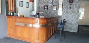 Un espace d’accueil avec un comptoir en bois, une caisse enregistreuse et des photographies encadrées accrochées au mur.
