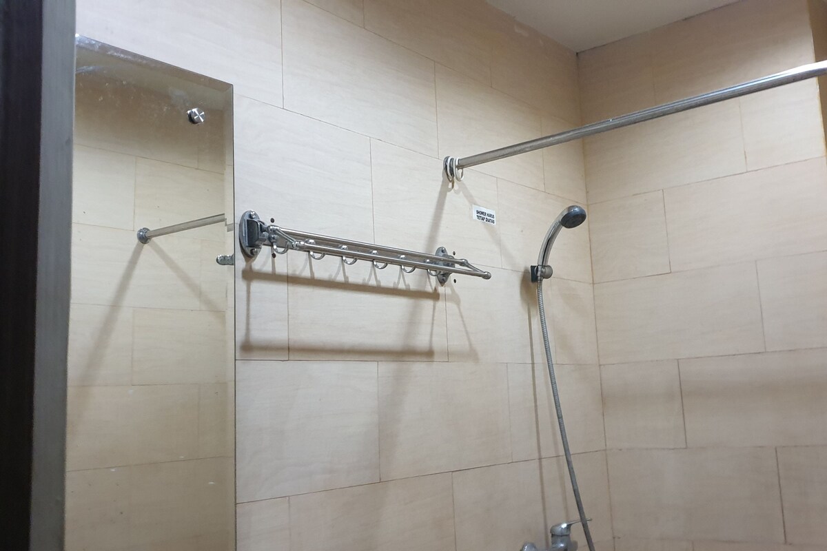 Un espace douche équipé d’une barre d’appui en métal, d’un pommeau de douche à main et d’un porte-serviettes.