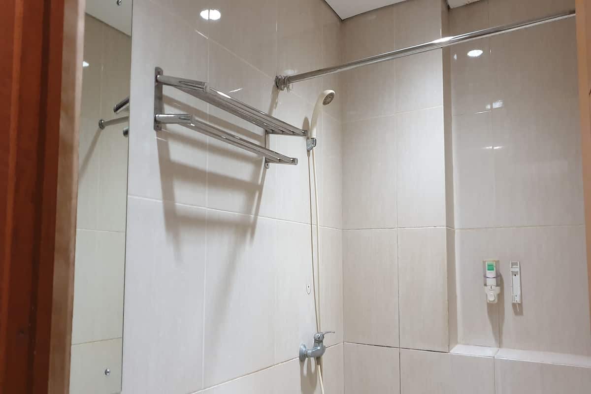 Un espacio de ducha con puerta de vidrio, un perchero y un panel de control en la pared.