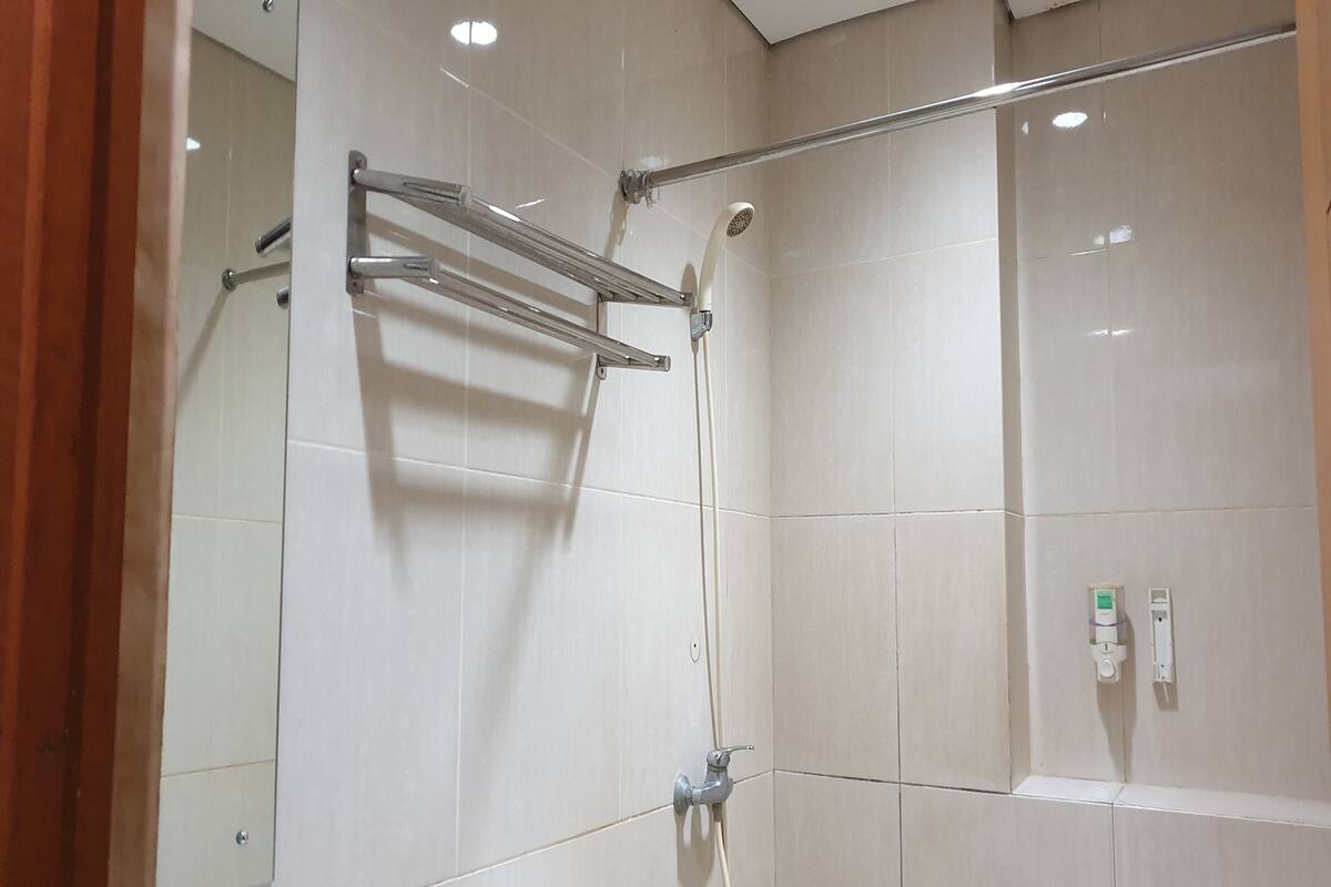 A shower area with a glass door, a towel rack, and a wall-mounted control panel.