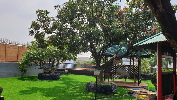 A well-maintained garden with a variety of trees, a gazebo, and a fenced area. - WIR Hotel by Zuzu (Lembongan Island)