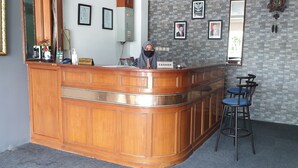 A reception area with a wooden counter, a receptionist, and a cashier. There are framed pictures on the wall and a clock. - WIR Hotel by Zuzu (Lembongan Island)
