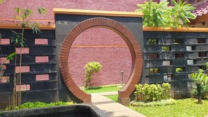 A brick archway leading to a building with a red textured wall and a tiled roof. - WIR Hotel by Zuzu (Lembongan Island)