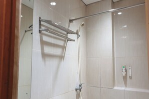 Un espace douche doté d’une porte en verre, d’un porte-serviettes et d’un panneau de commande fixé au mur.