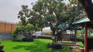 Un jardin bien entretenu, agrémenté de divers arbres, d’un belvédère et d’une zone délimitée par une clôture.