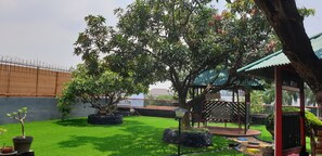 Un jardin bien entretenu, agrémenté de divers arbres, d’un belvédère et d’une zone délimitée par une clôture.
