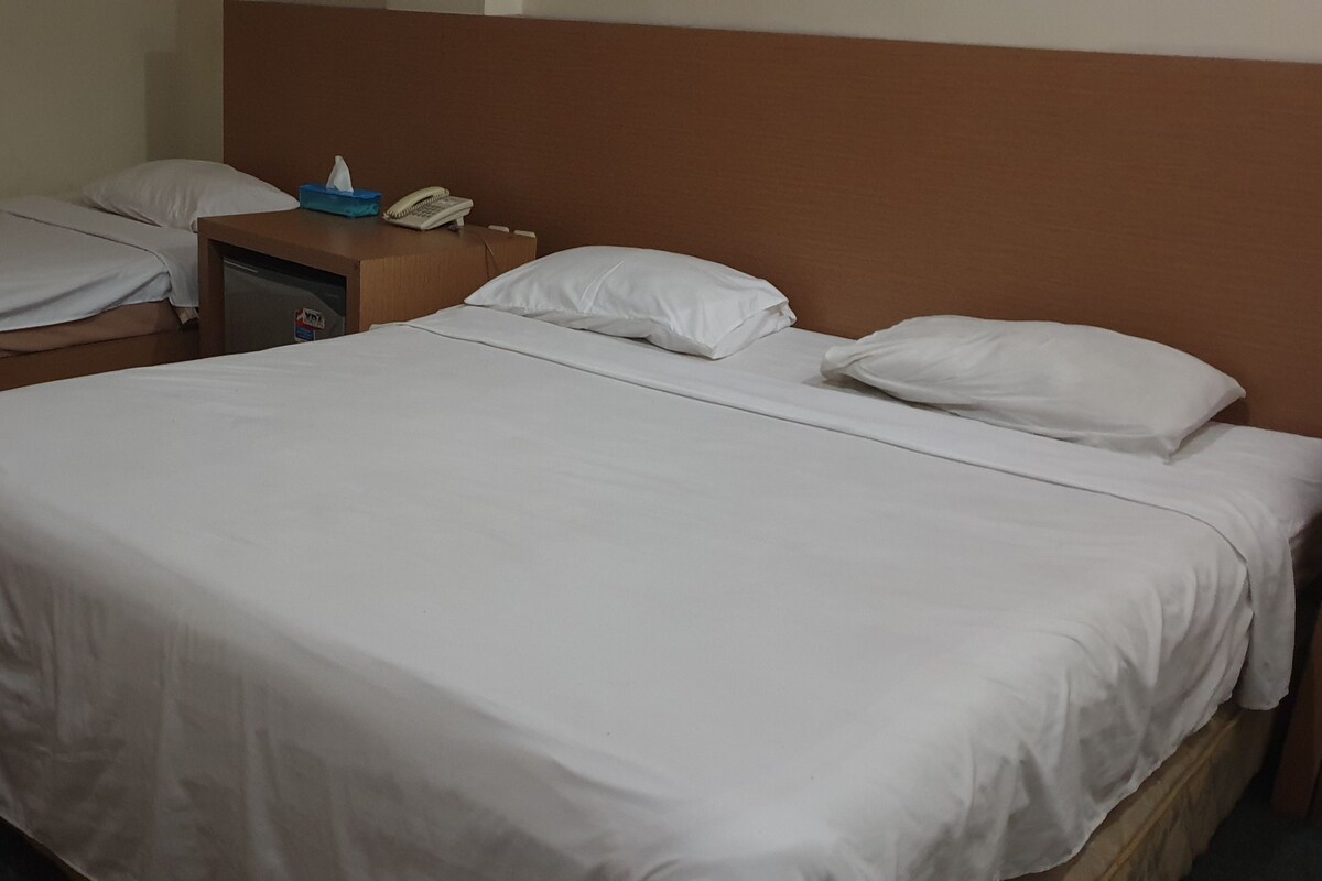 Une chambre d’hôtel avec deux lits simples, une table de chevet avec un téléphone et une tête de lit.