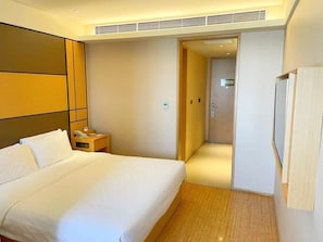 Une chambre d’hôtel avec un grand lit, une table de chevet avec un téléphone et une porte donnant sur une salle de bain.