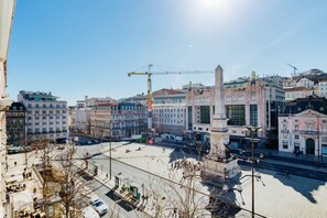 Ein historischer Platz mit einem markanten Denkmal, umgeben von klassischer Architektur und einem Baukran im Hintergrund.