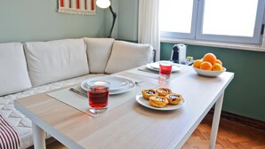 A dining table with a plate of pastries, a glass of red drink, and a bowl of oranges. - Mojito Breeze in Lisbon by Misha s Place 3C (Lisbon)
