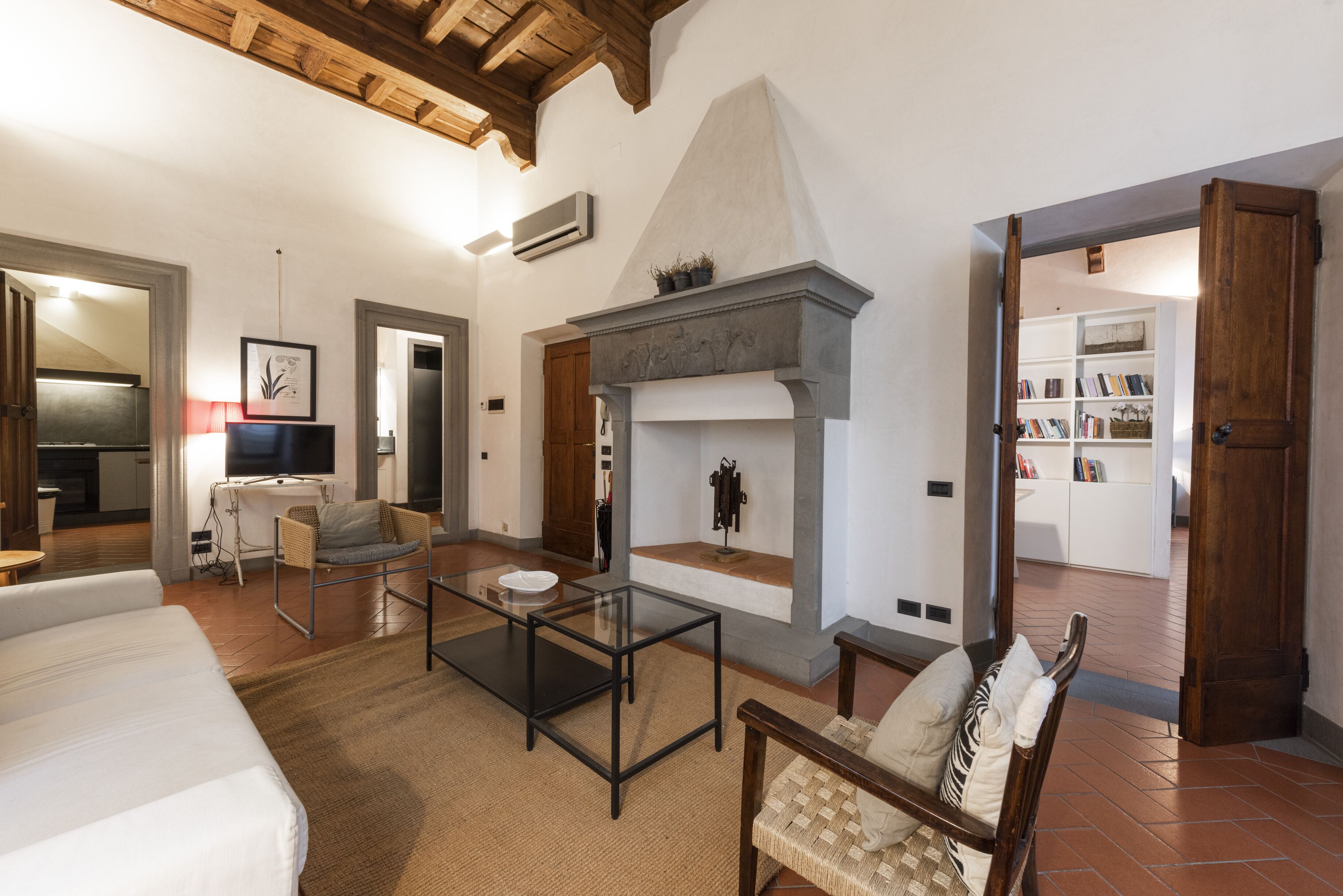 A spacious living room with a fireplace, a sofa, a coffee table, and a bookshelf.