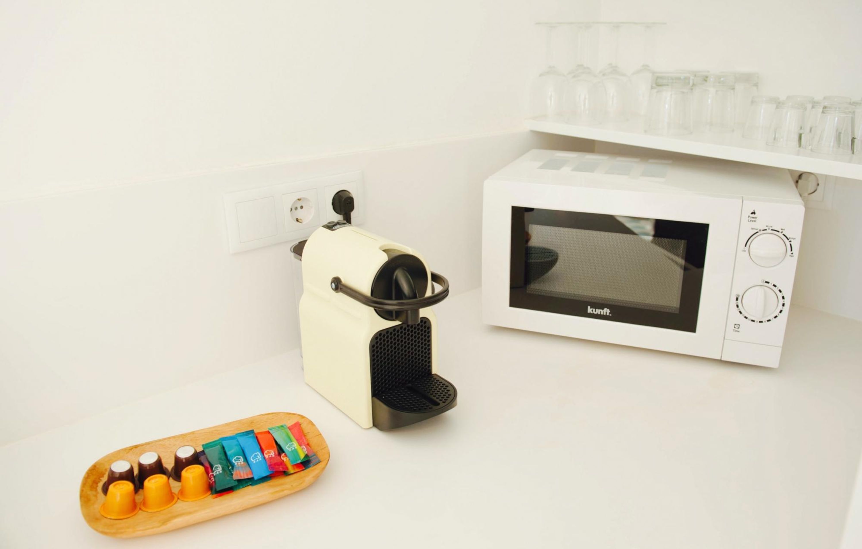 A kitchen with a microwave, a toaster, and a tray of colorful cups.