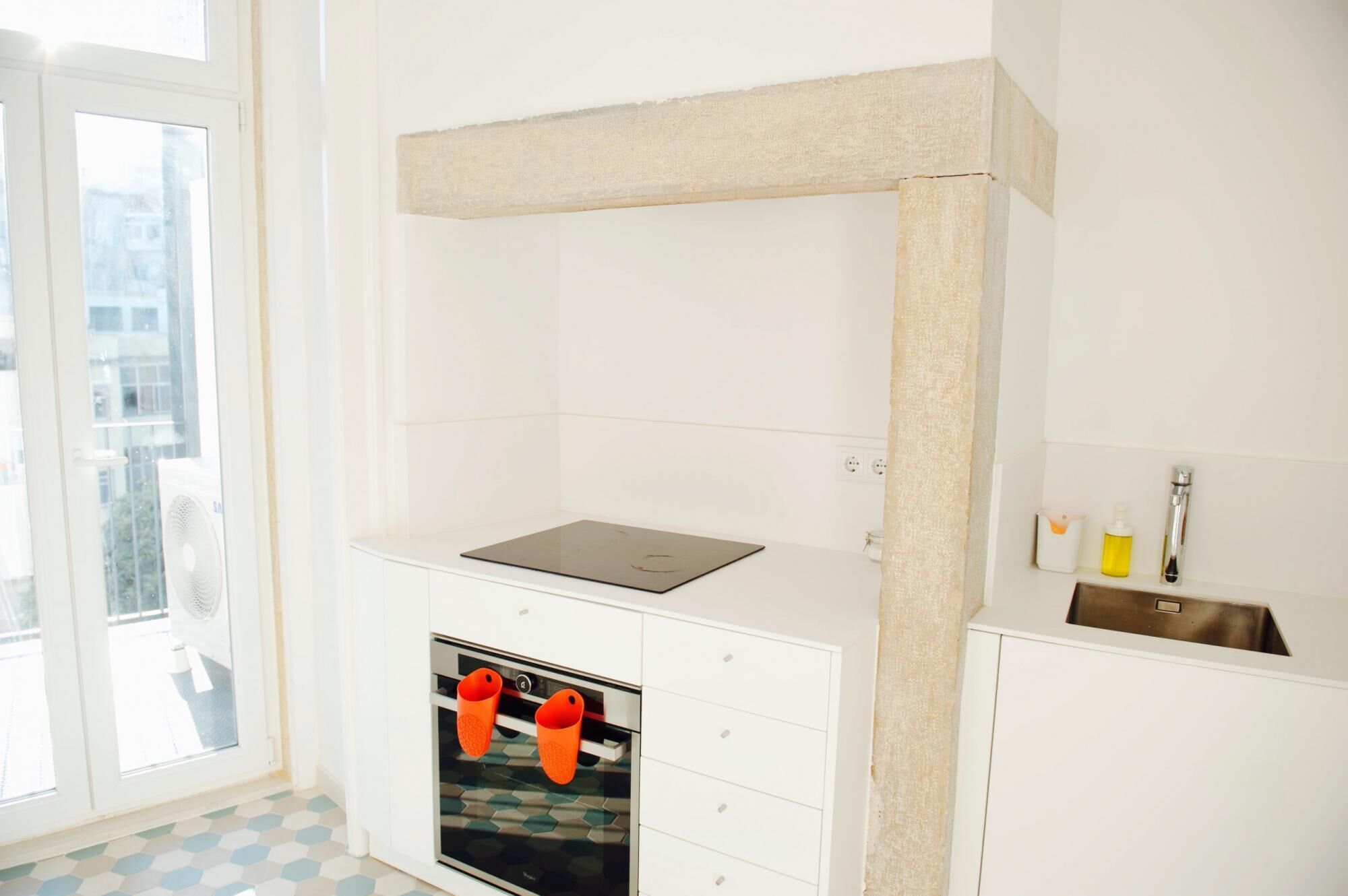 Eine Küche mit Backofen, weißer Arbeitsplatte und einem Fenster mit Blick auf Gebäude.