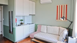 A modern living space with a kitchenette, a sofa, a lamp, and a striped curtain. - Expresso Martinis in Lisbon by Misha s Place 4c (Lisbon)