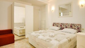 A bedroom with a bed, a red chair, a wardrobe, and a mirror on the wall. - Villa Apartments Babaja (Dugi Rat)