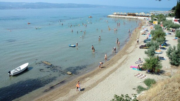 A beach with clear water, umbrellas, and a boat. - Villa Apartments Babaja (Dugi Rat)