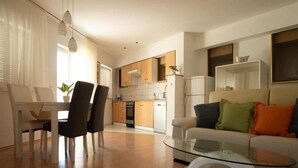 A modern living room with a glass coffee table, a sofa with colorful cushions, and a dining area with chairs and a table. - Villa Apartments Babaja (Dugi Rat)
