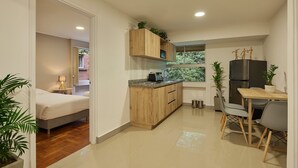 Une cuisine de taille réduite, dotée de meubles en bois, d’un réfrigérateur et d’un coin repas avec des chaises.