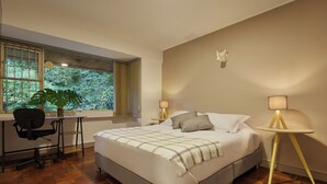 Une chambre à coucher comprenant un lit, un bureau, une chaise et une fenêtre donnant sur un paysage verdoyant.