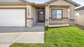A two-story house with a garage, stone accents, and a well-maintained lawn. - Comfortable New Home in Broadmoor Subdivision (Twin Falls)