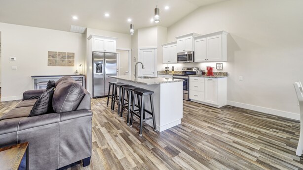 A modern kitchen with white cabinets, a central island, and a bar stool seating area. - Comfortable New Home in Broadmoor Subdivision (Twin Falls)