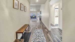 A hallway with a wooden bench, a patterned rug, and framed artwork on the wall. - Comfortable New Home in Broadmoor Subdivision (Twin Falls)