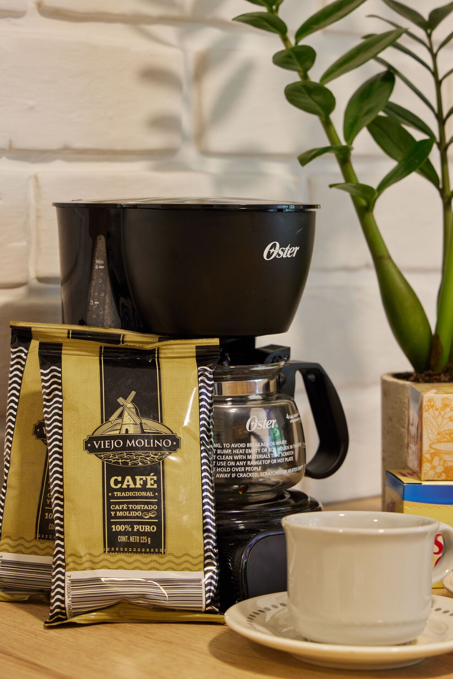 Een koffiezetapparaat, een kop en koffiezakjes op een tafel.