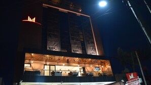 A hotel with a terrace on the upper floor, a sign indicating it offers breakfast, and a bright light in the sky. - Millennium Terrace Hotel (Kampala)