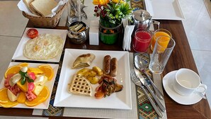 A breakfast table with various food items, a plant, and a coffee pot. - Millennium Terrace Hotel (Kampala)