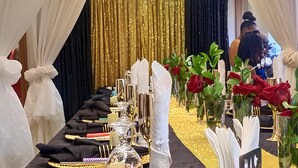 A banquet table set with gold and black tableware, white napkins, and red roses. - Millennium Terrace Hotel (Kampala)