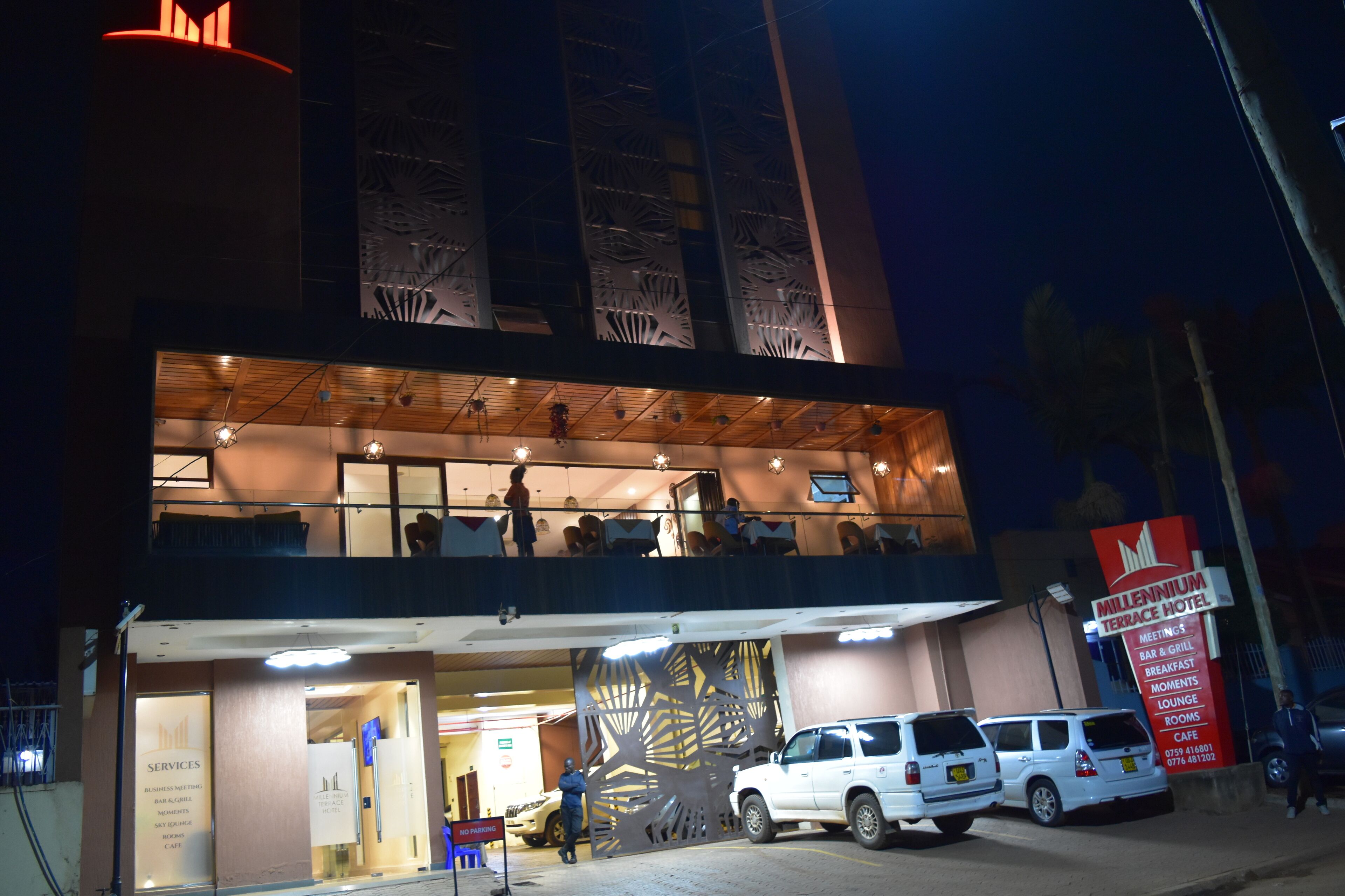 Un hotel de dos pisos, con un balcón en el piso superior y un cartel que enumera servicios como salas de reuniones y una cafetería.